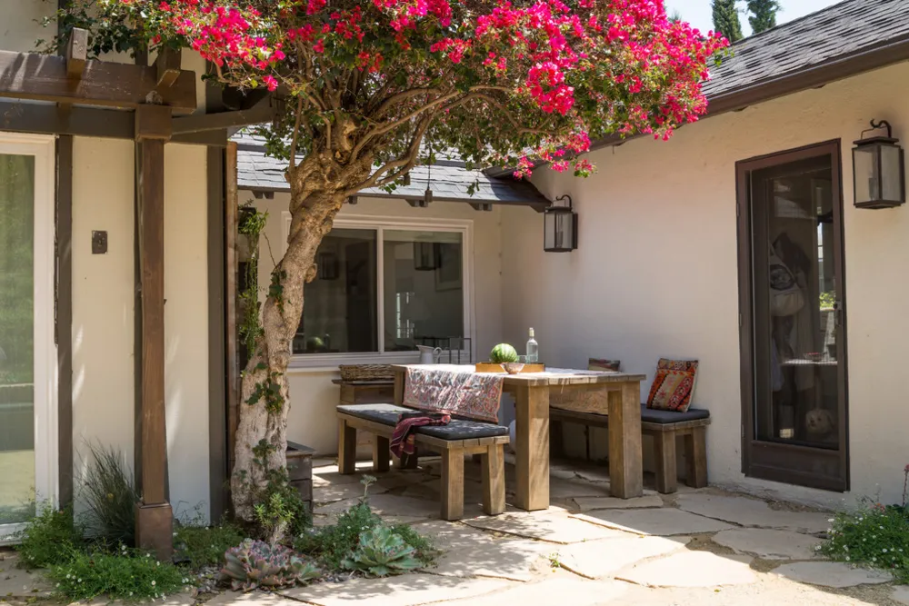 Lässiger Essbereich im Freien neben Haus mit Bougainvillea